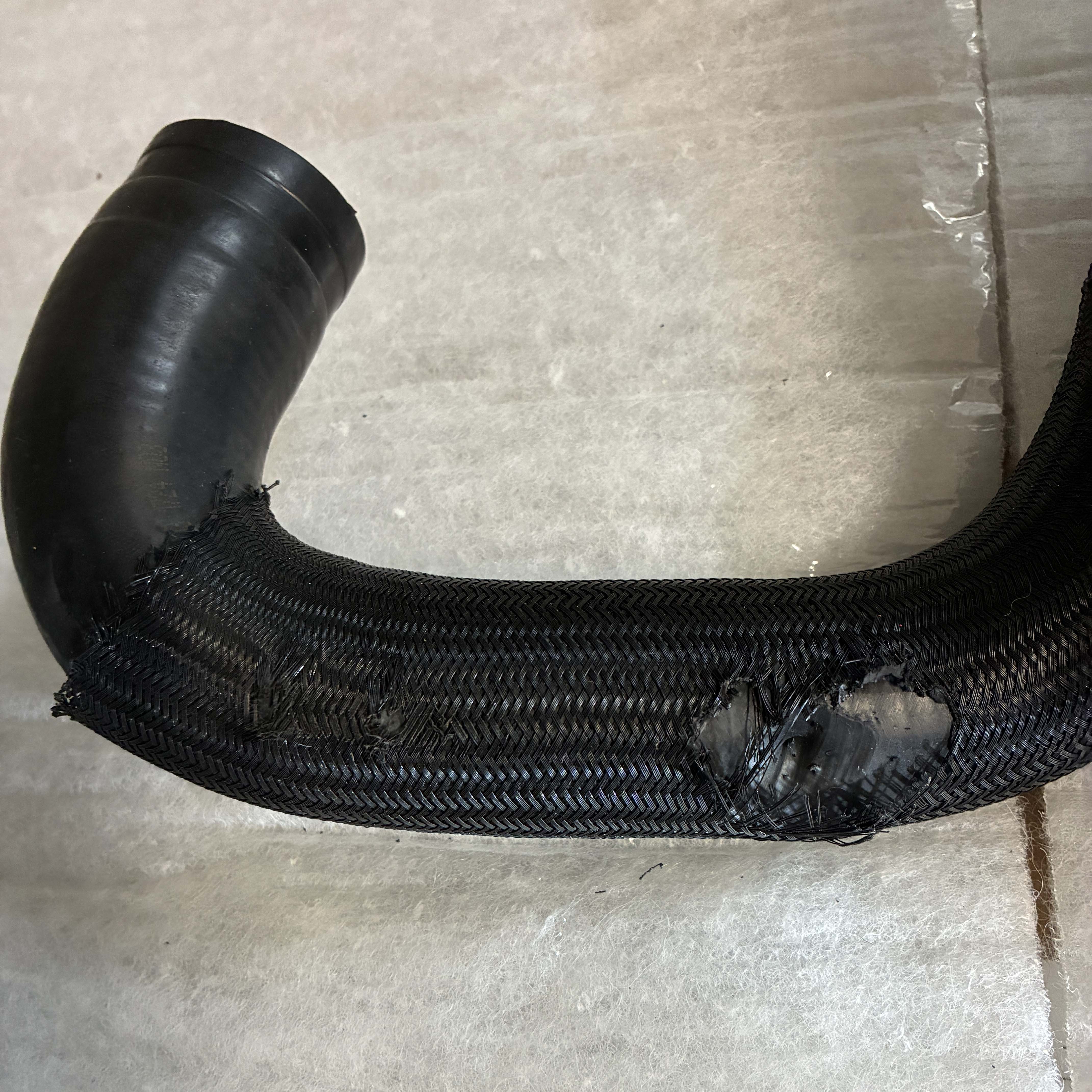 uppper coolant hose showing wear from contact with pulley.